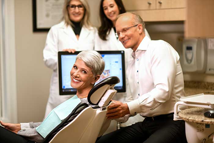 The dentist explains woman in the dentist chair how oral cancer screenings work